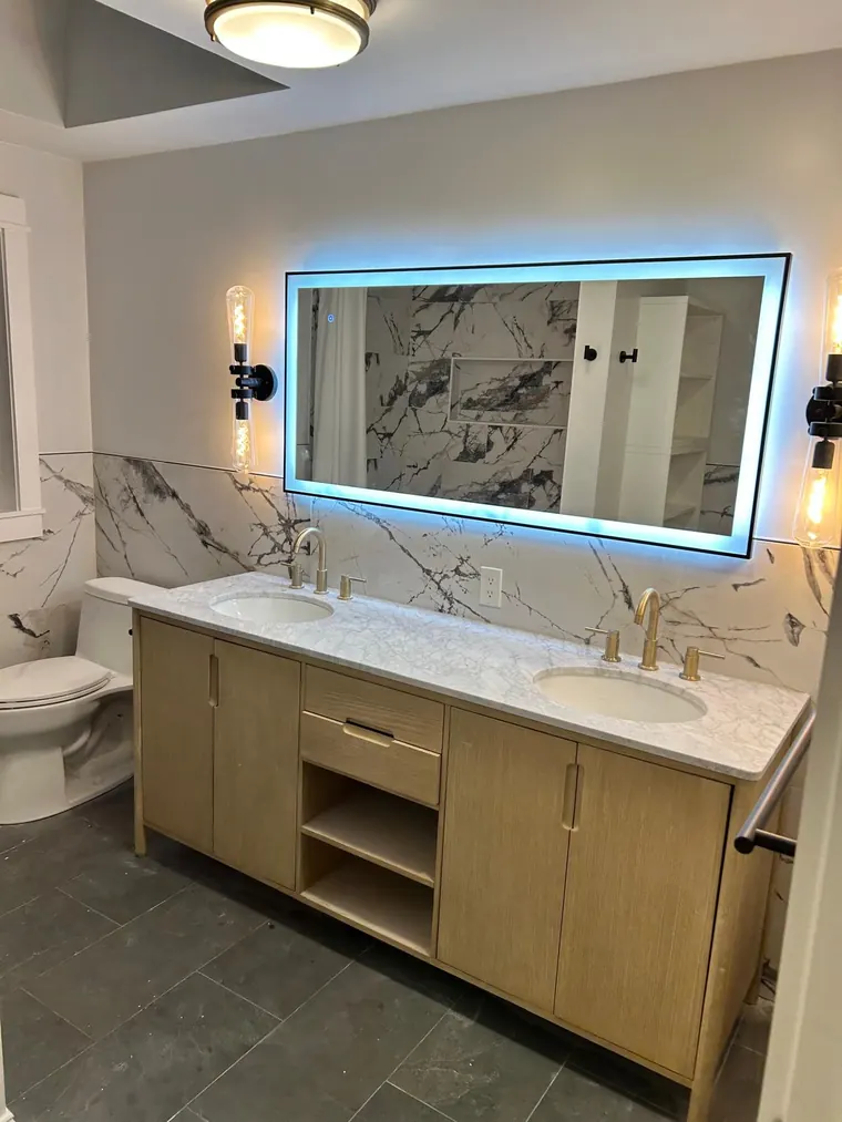 Double vanity with an LED mirror against a marble slab wall