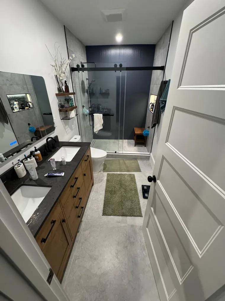 Glass shower enclosure beside a dark vanity in a finished bathroom