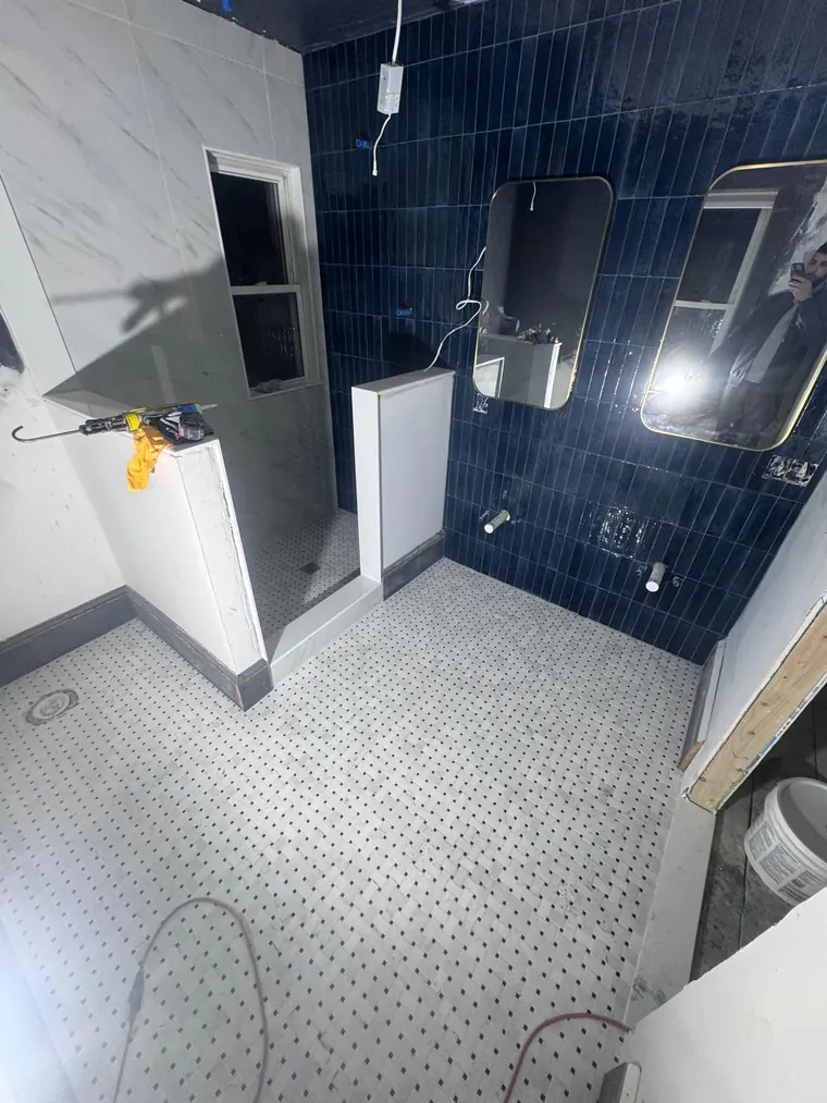Navy blue tile shower wall with a mosaic tile floor